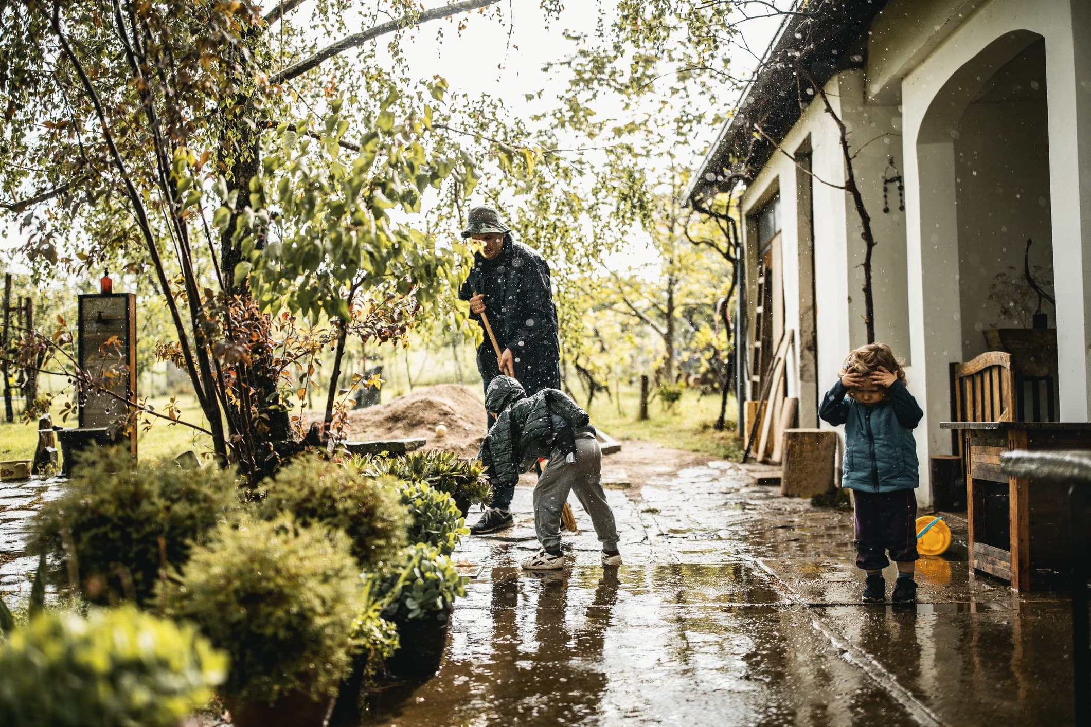 A father and son sweeping floodwater from their front yard on a rainy day